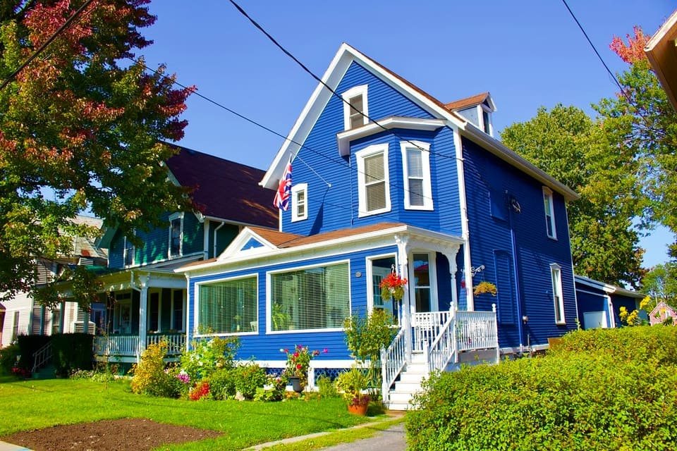 A bright blue two-storey home with a welcoming front porch on a sunny day