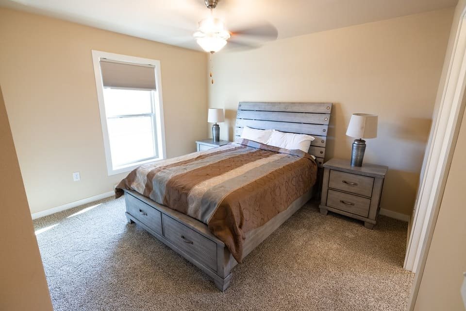 A tidy bedroom with a made double bed, striped quilt, nightstands and lamps