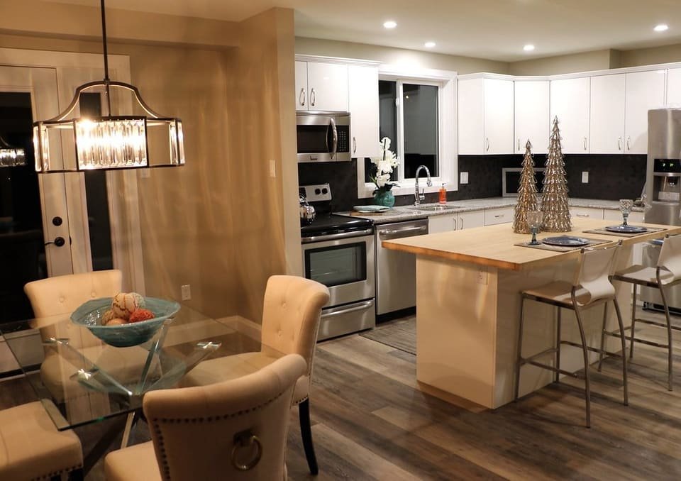 A dining table with upholstered chairs beside a modern kitchen