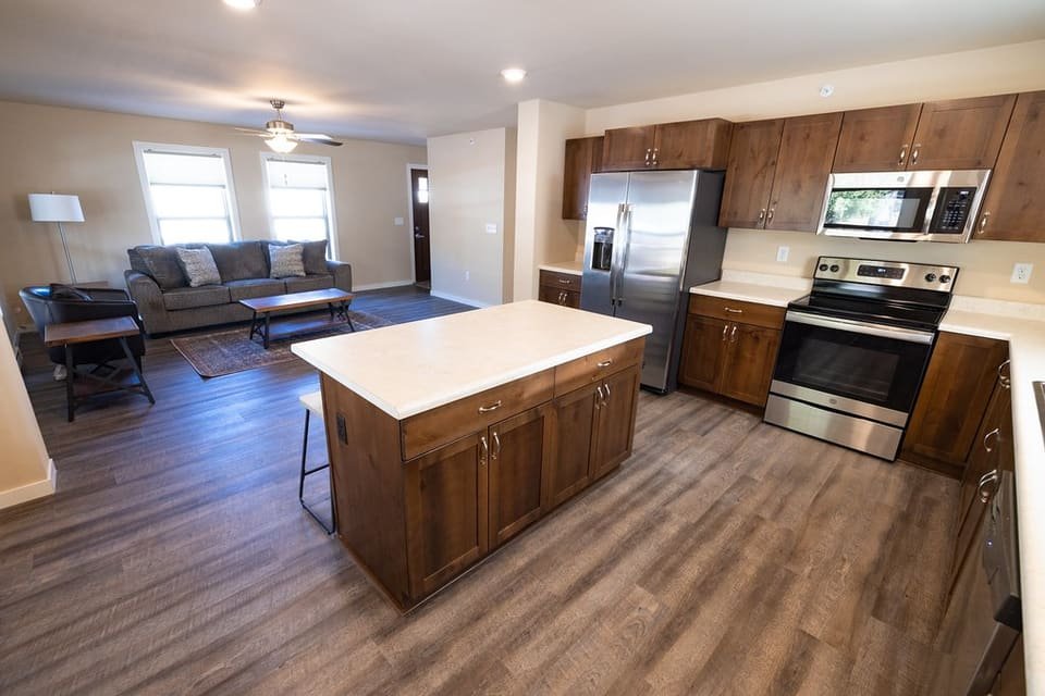 An open kitchen with an island, stainless appliances and a living area beyond